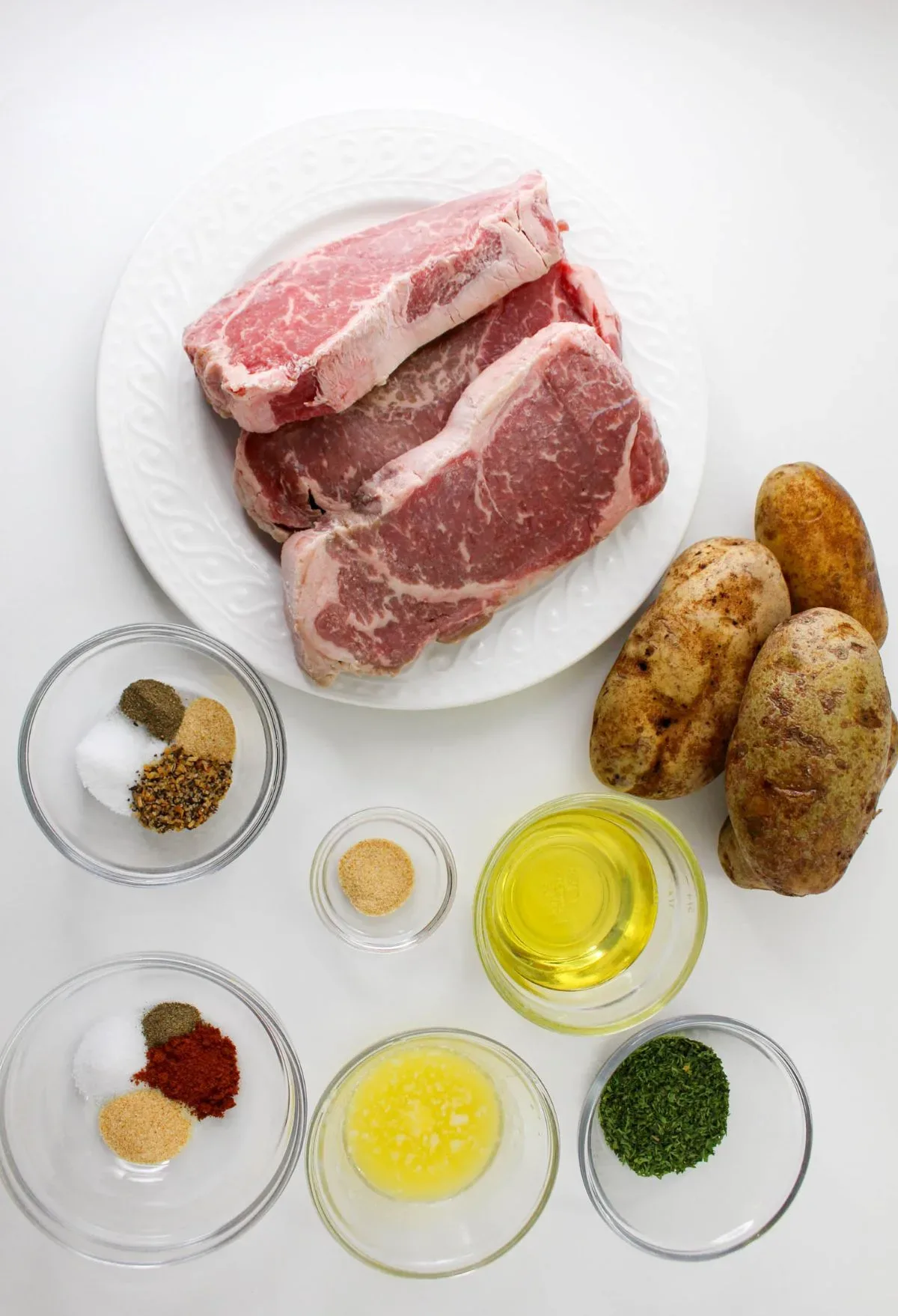 A plate with steak, potatoes and other ingredients on a white background.