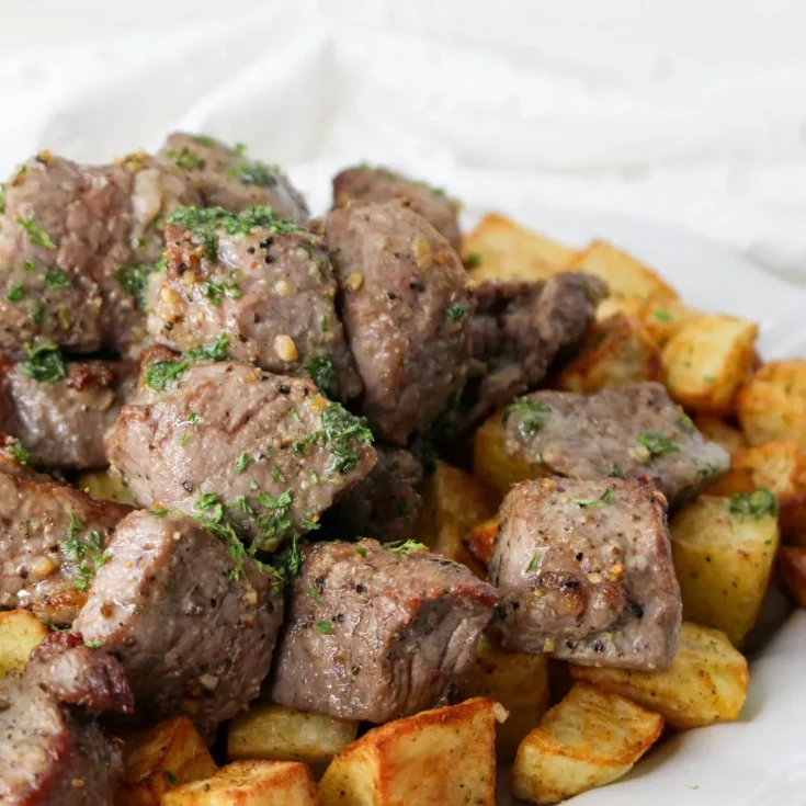 A plate of meat and potatoes on a white plate.