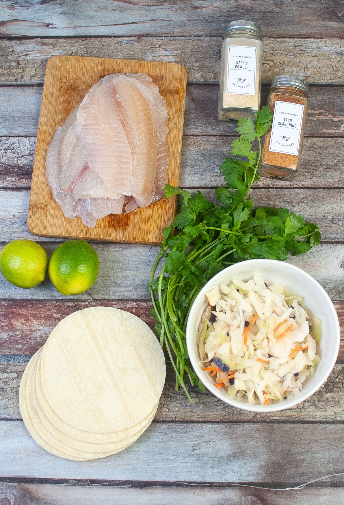 A bowl of tortillas and limes on a wooden table.