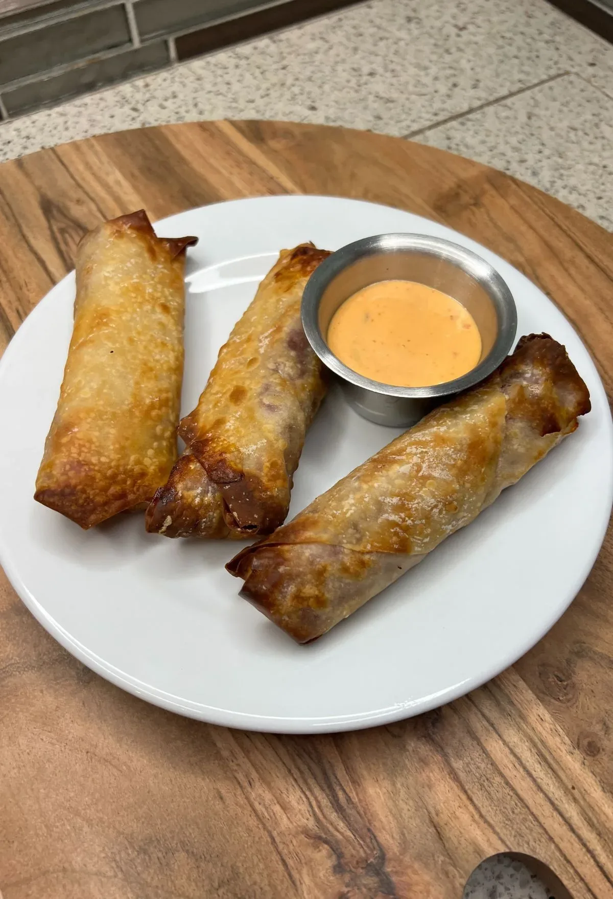 Spring rolls with dipping sauce on a white plate.