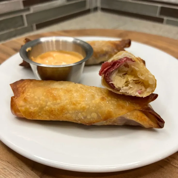 Ham and cheese spring rolls on a plate with dipping sauce.