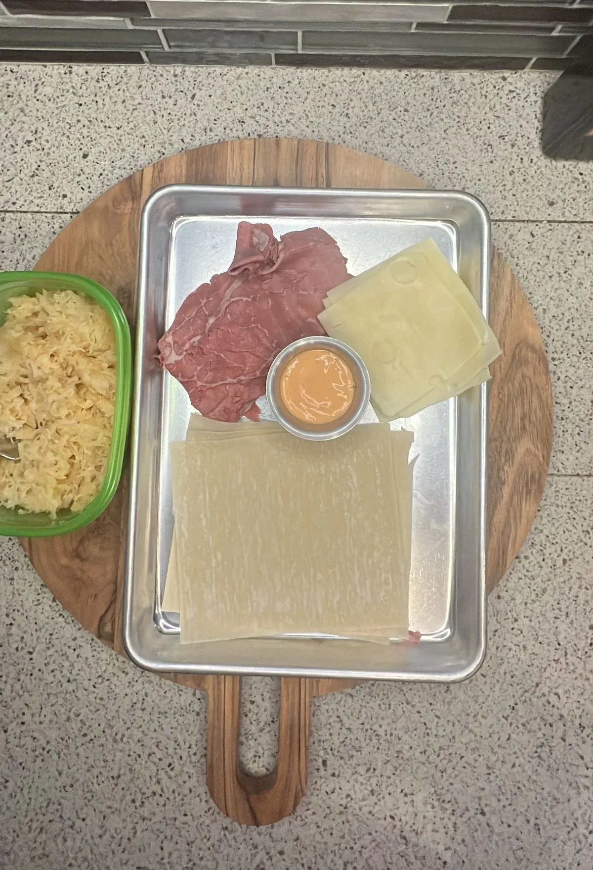 A tray with meat, cheese and sauce on it.