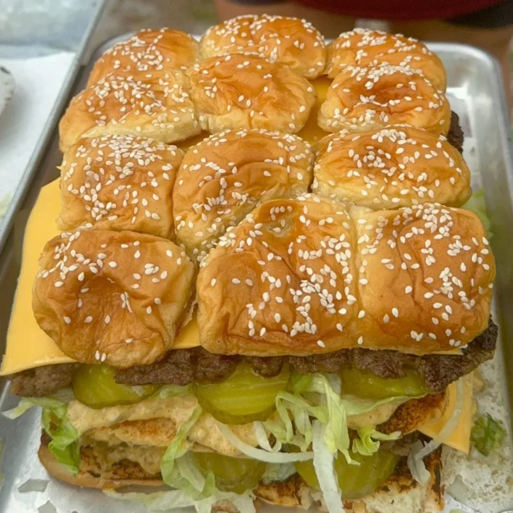 A large burger sandwich is sitting on a tray.
