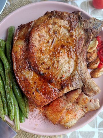 A plate with grilled pork chops and green beans.