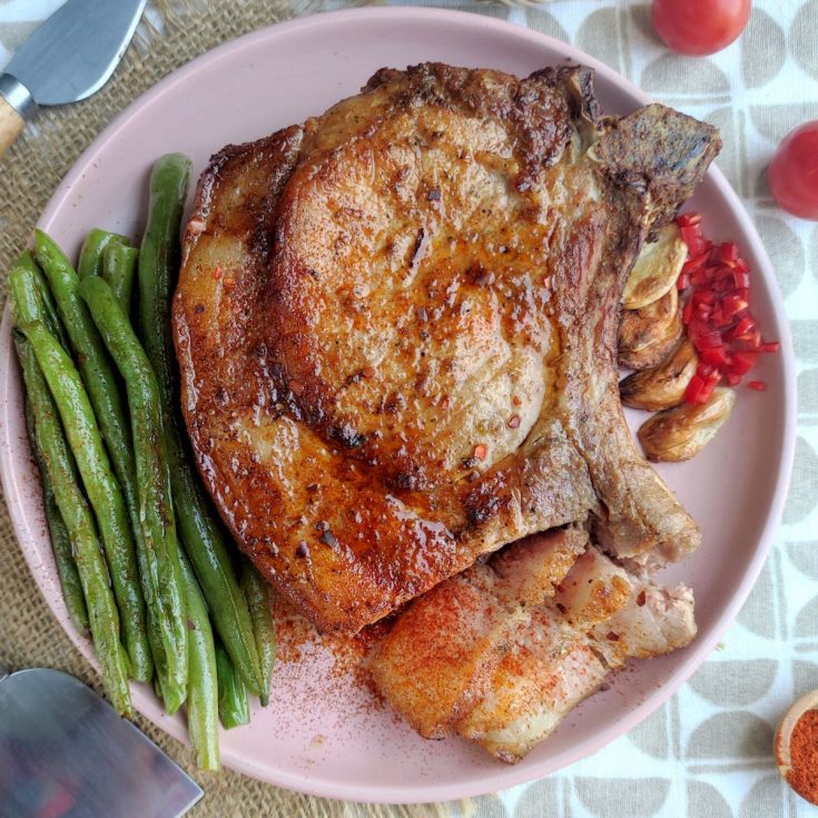 A plate with grilled pork chops and green beans.