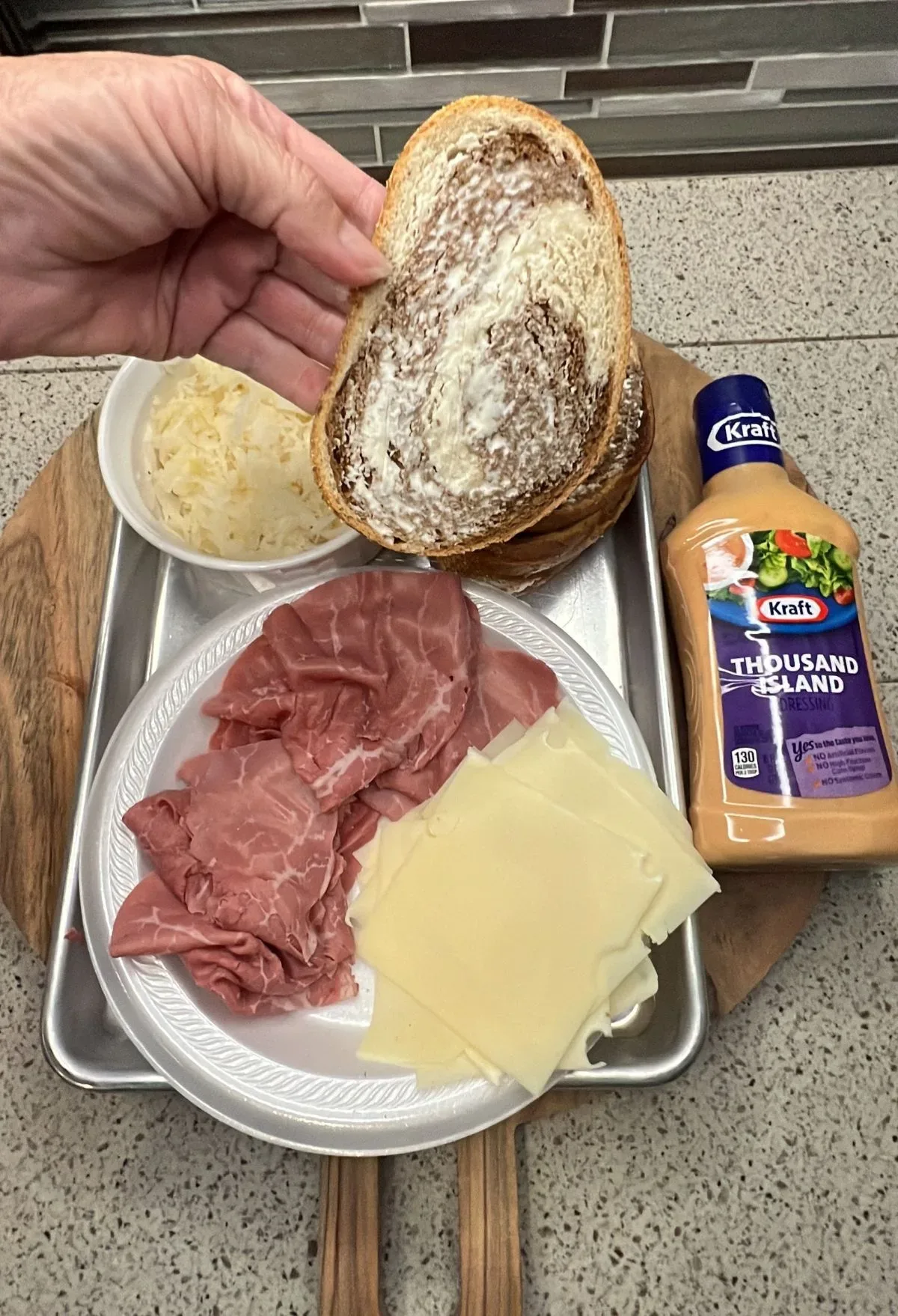 A person is holding a plate with meat and cheese on it.