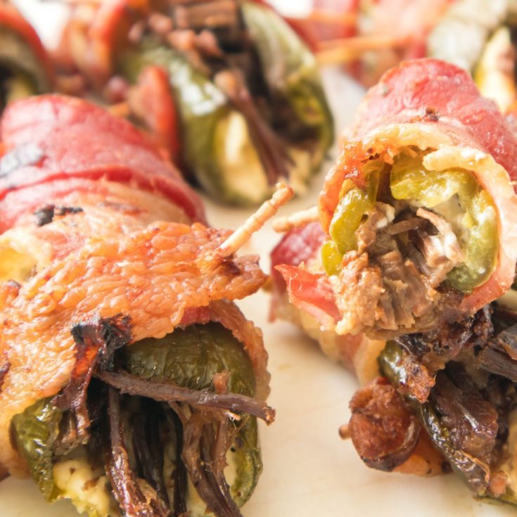 Brisket Stuffed Peppers wrapped in bacon, served on a plate.