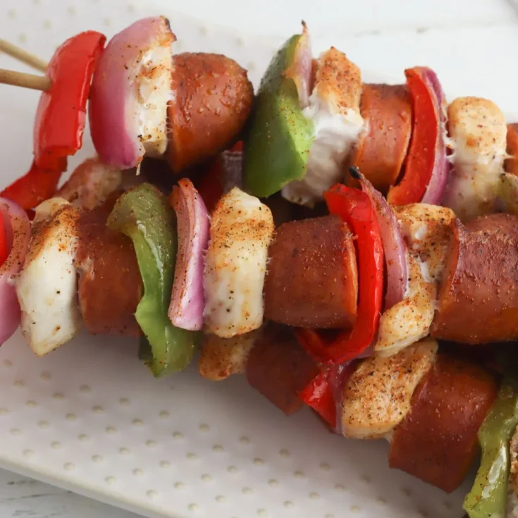 Hot dog skewers with peppers and onions on a plate.