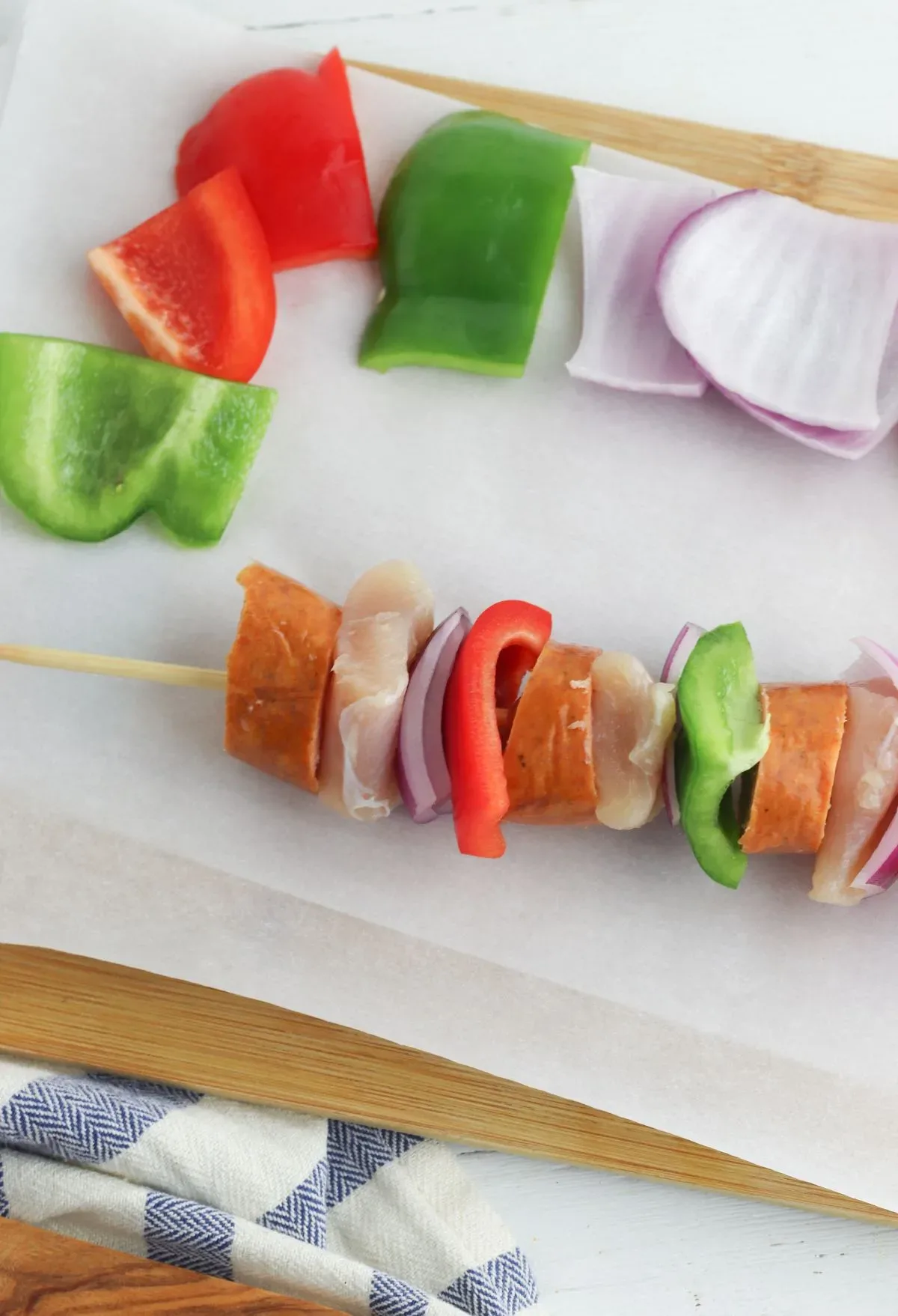 Sausage skewers with peppers and onions on a cutting board.