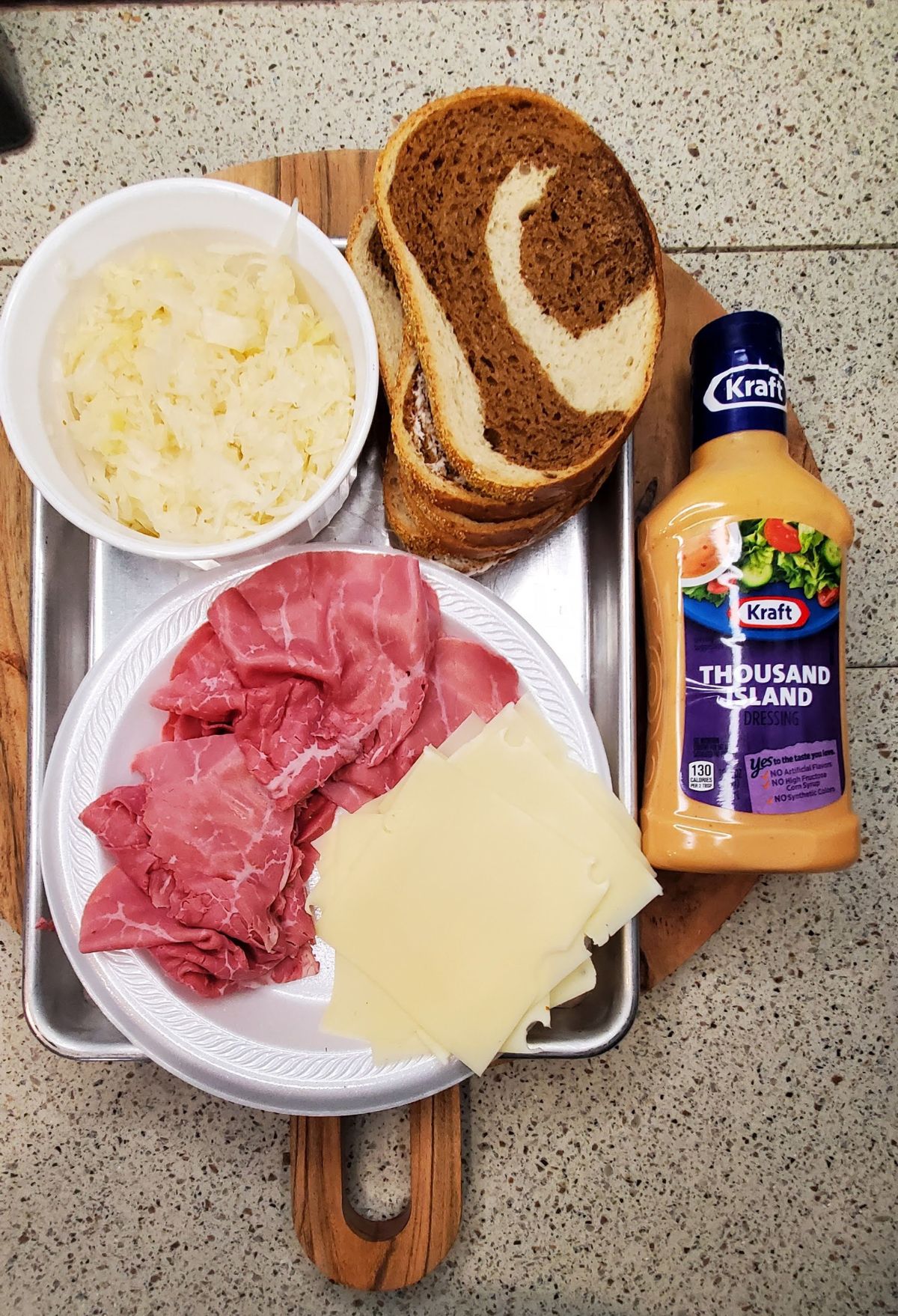 A plate with ham, cheese, and a bottle of ranch dressing.